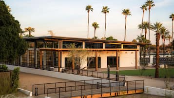 A modern building with a flat roof, large windows, and a covered outdoor area with a railing.