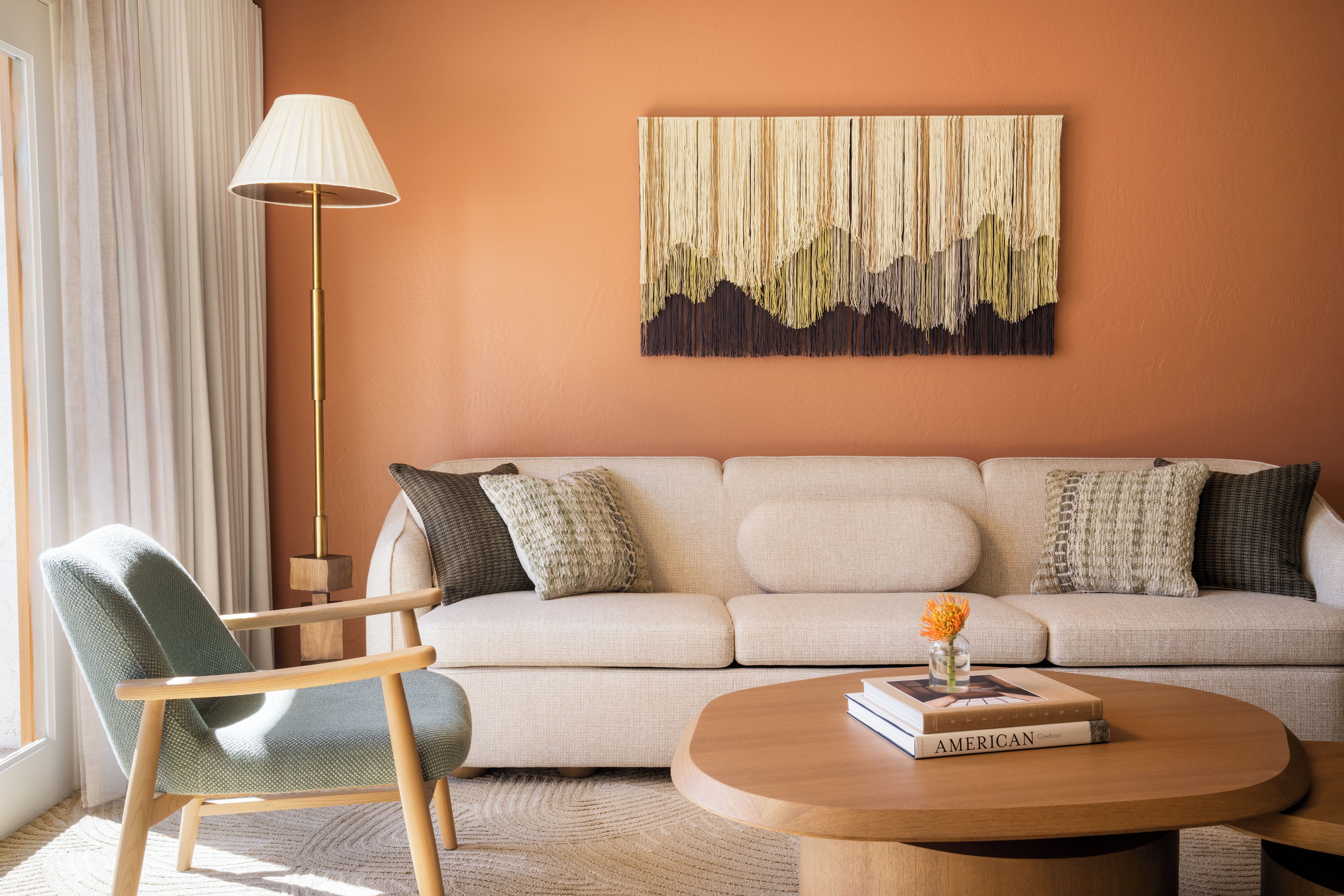 A living room with a sofa, a chair, a lamp, a coffee table, and a wall art piece.
