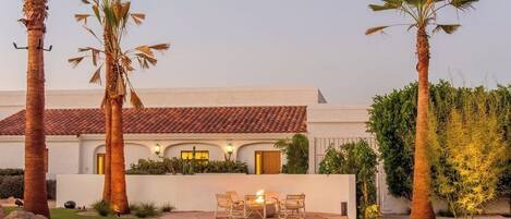 A house with a patio, palm trees, and a fire pit.