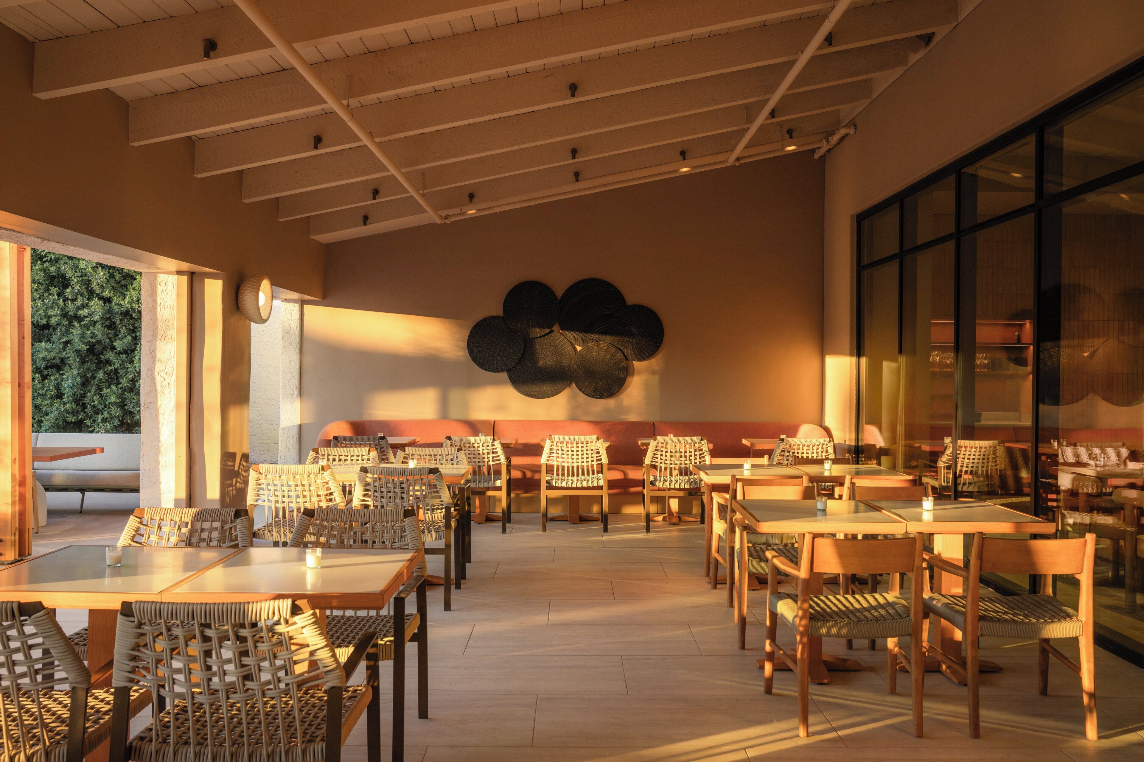 A spacious restaurant with high ceilings, modern furniture, and a large decorative wall.