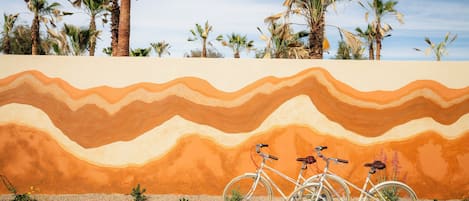 A bicycle parked in front of a wall with a desert landscape mural.