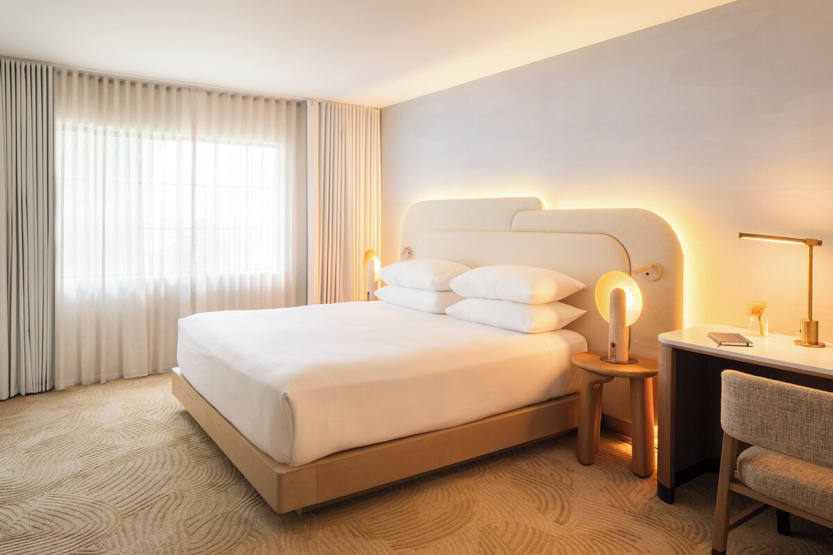 A hotel room with a large bed, a desk, and a chair.