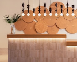 A reception desk with a wooden finish, multiple light fixtures, and a decorative wall panel.