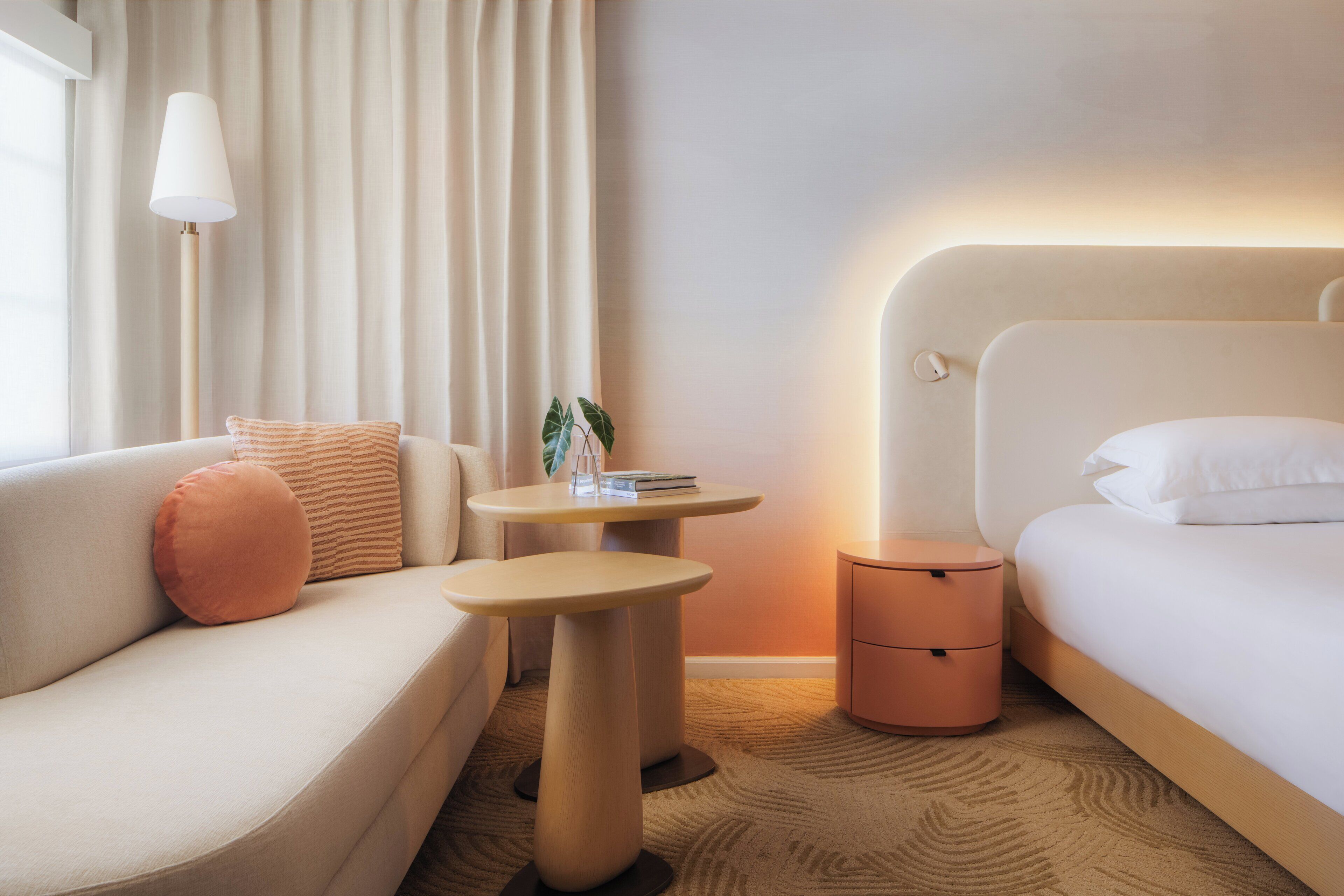 Una habitación de hotel con sofá, una mesita redonda, una mesita de noche y cama.