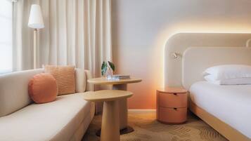 Una habitación de hotel con sofá, una mesita redonda, una mesita de noche y cama.