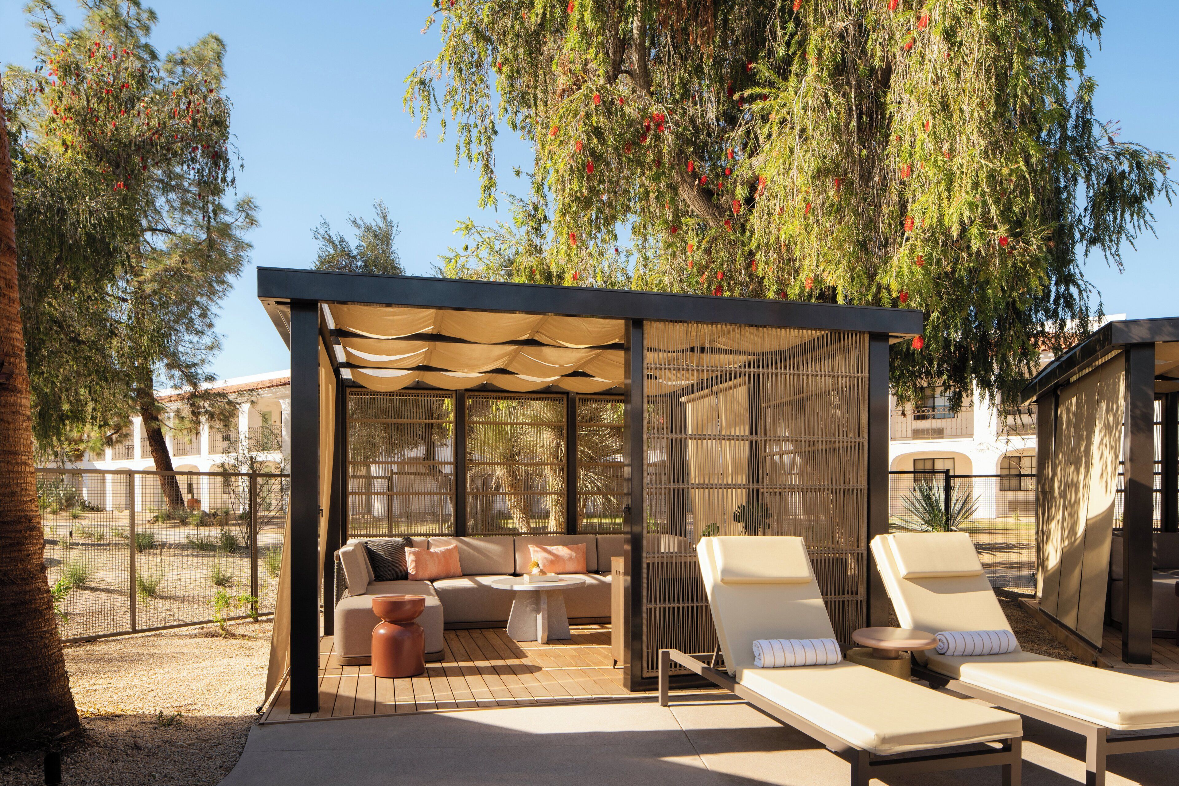 A covered outdoor seating area with a sofa, two lounge chairs, and a small table.