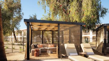 Un espacio de estar al aire libre cubierto con un sofá, dos sillones y una mesita.