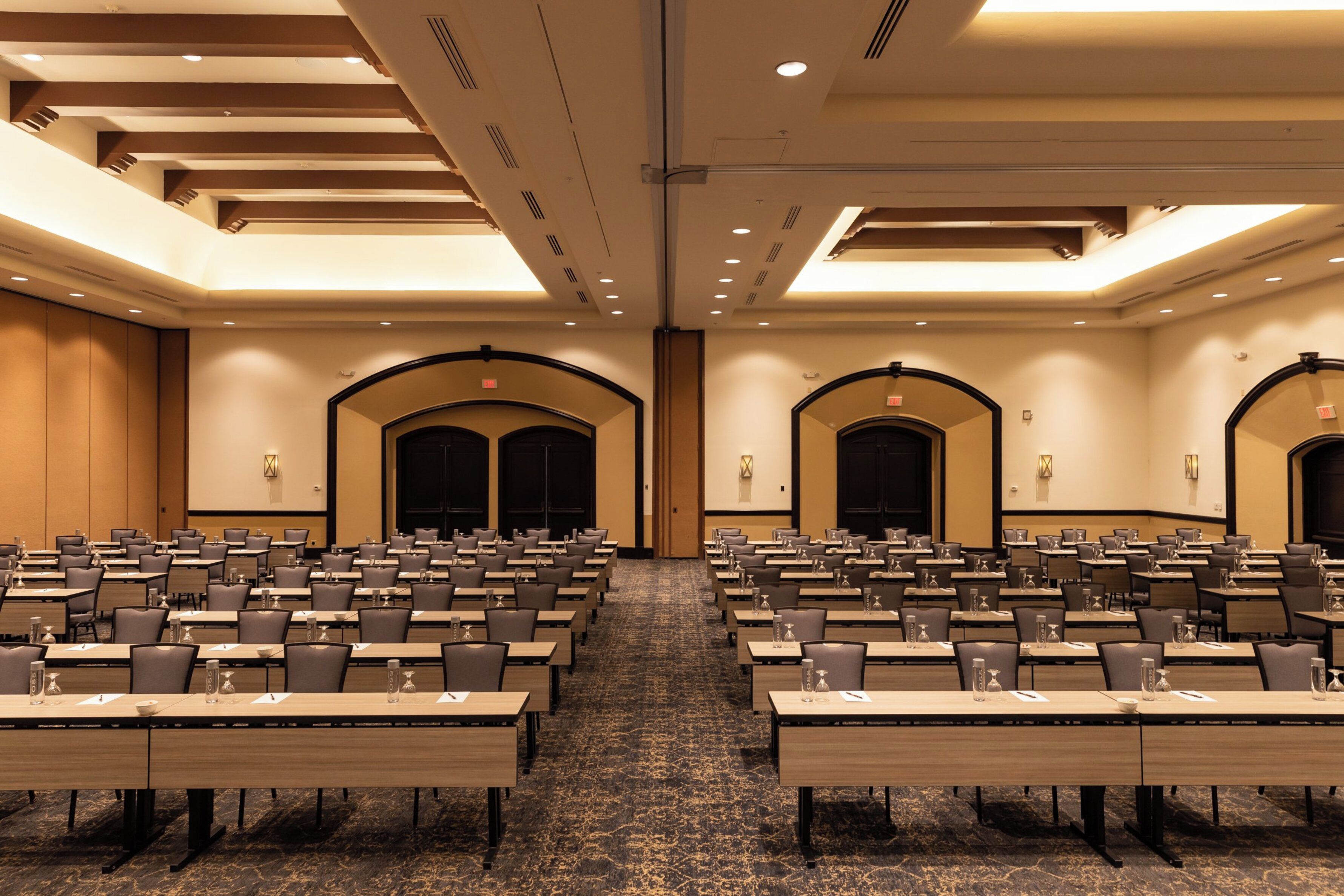 A conference room with multiple tables and chairs, equipped with water bottles and nameplates.