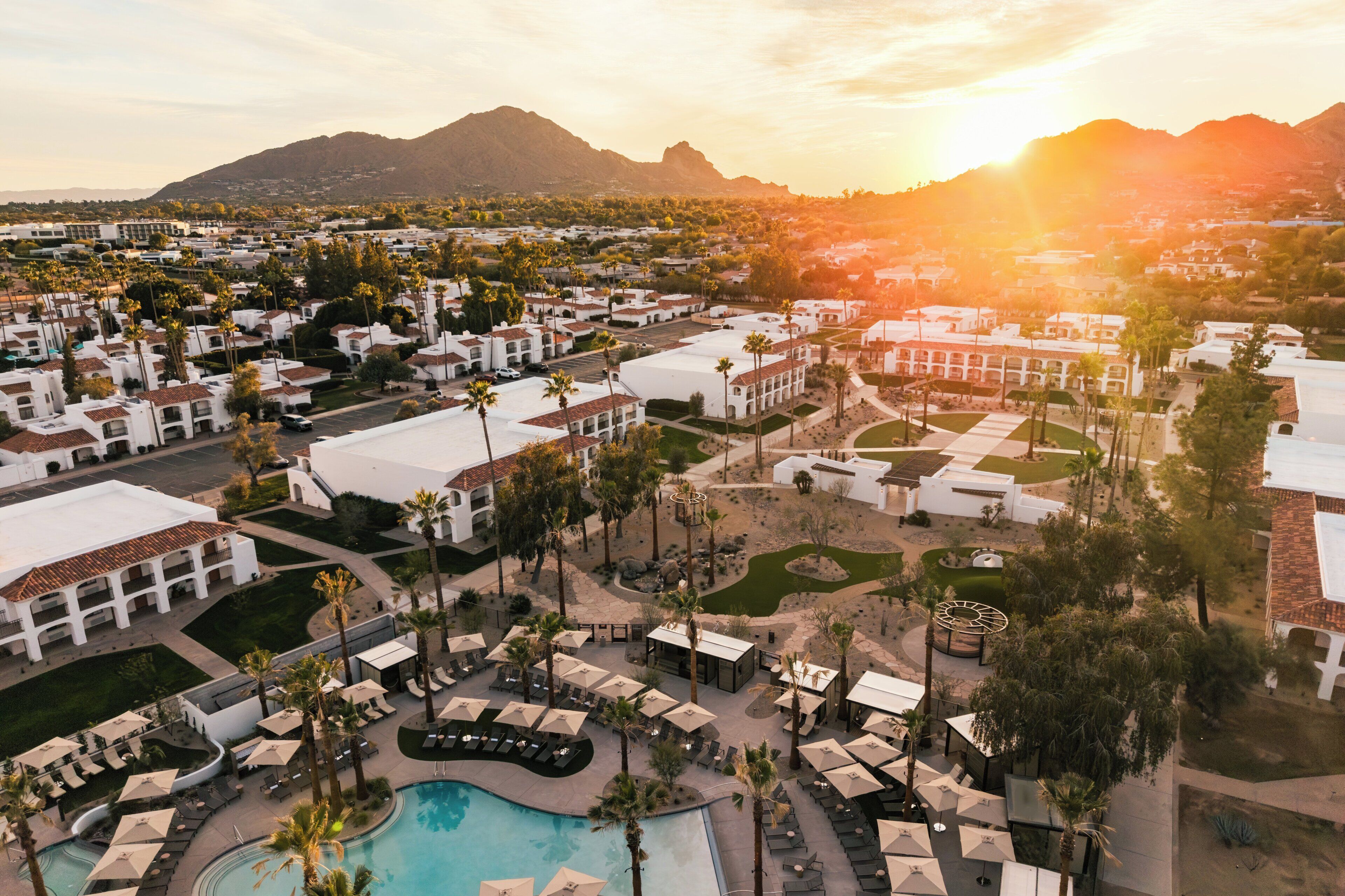 A resort with multiple buildings, a swimming pool, and palm trees.