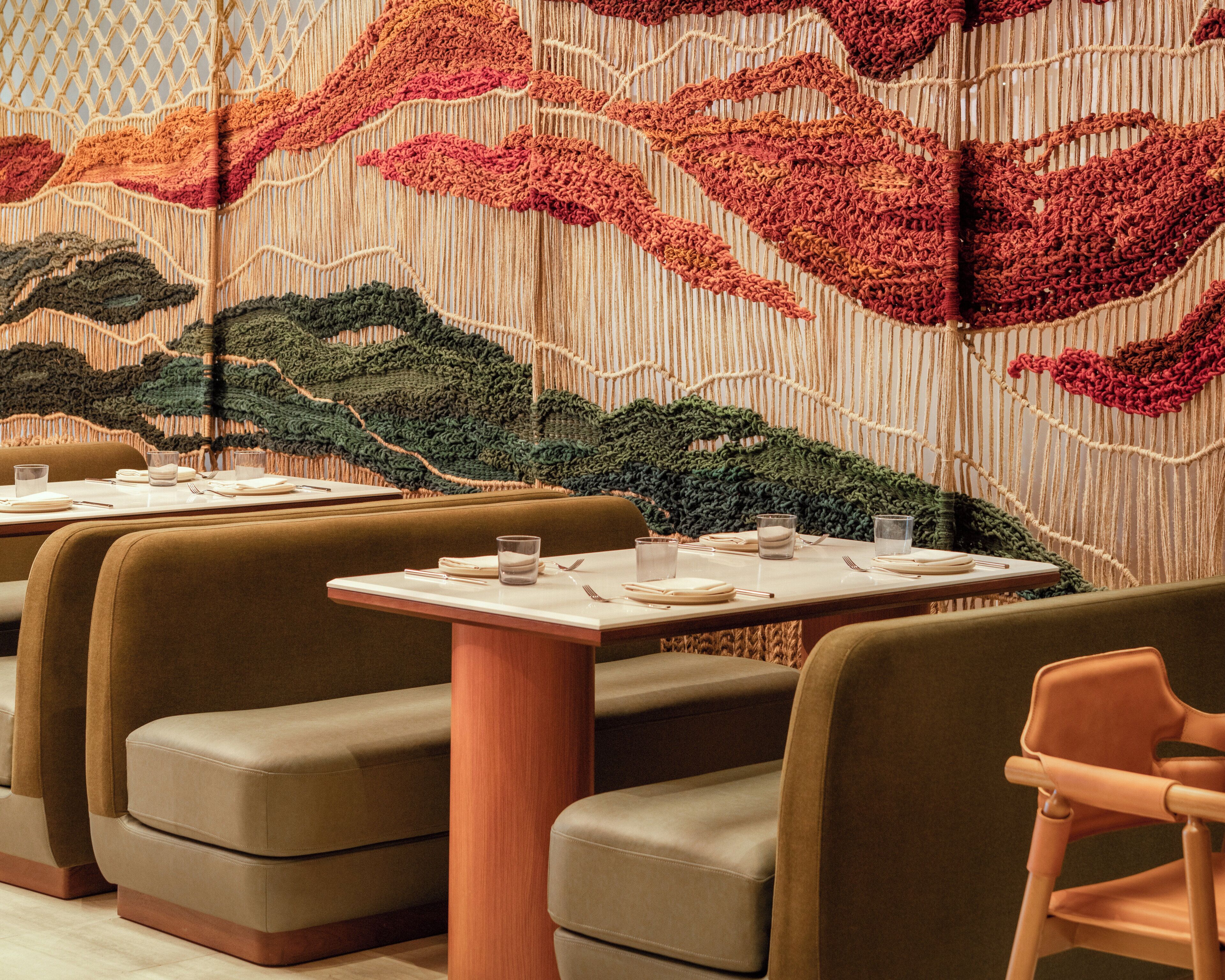 A restaurant interior with booth seating and a macramé wall.