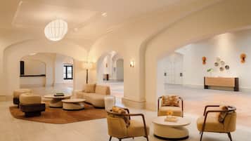 A spacious lobby with modern furniture, arched ceilings, and a central light fixture.