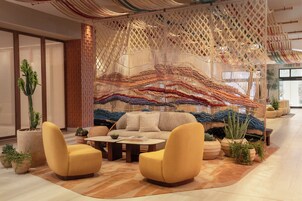 Una sala de estar moderna con un sofá, dos sillones, una mesita de centro y un adorno de macramé en la pared.