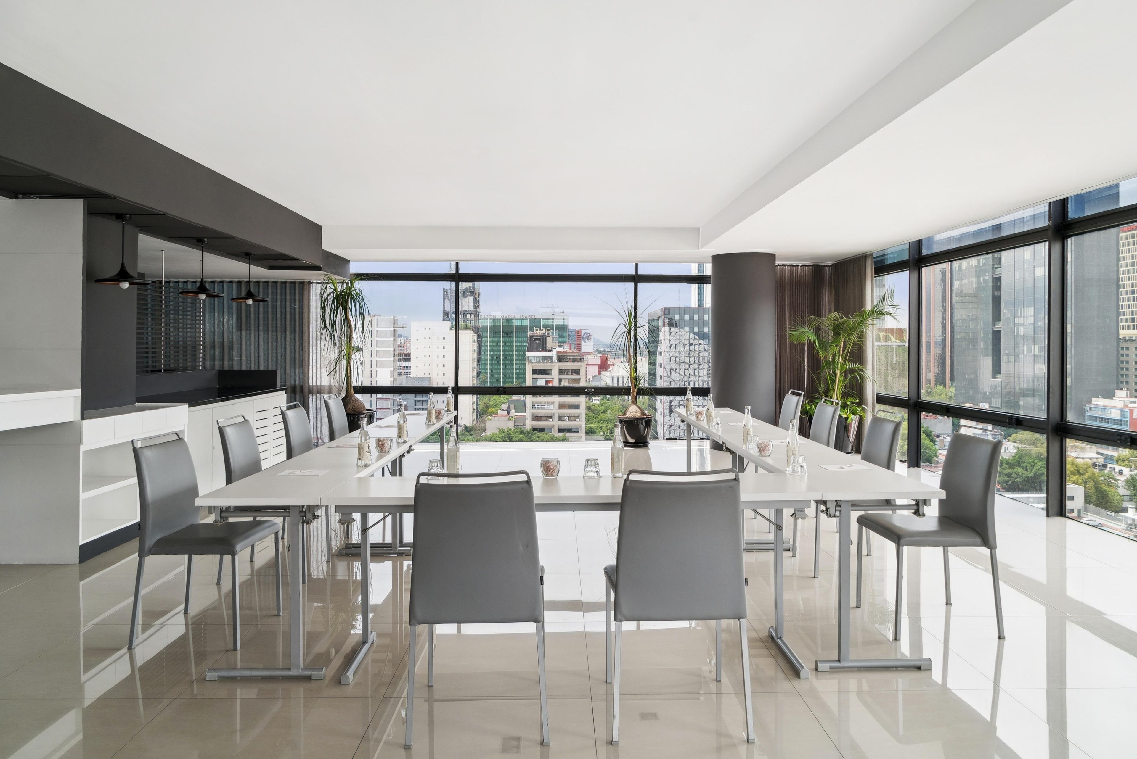 Un comedor moderno con una mesa larga y sillas, ventanas amplias con vista a la ciudad y un diseño minimalista.