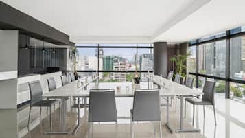 Un comedor moderno con una mesa larga y sillas, ventanas amplias con vista a la ciudad y un diseño minimalista.