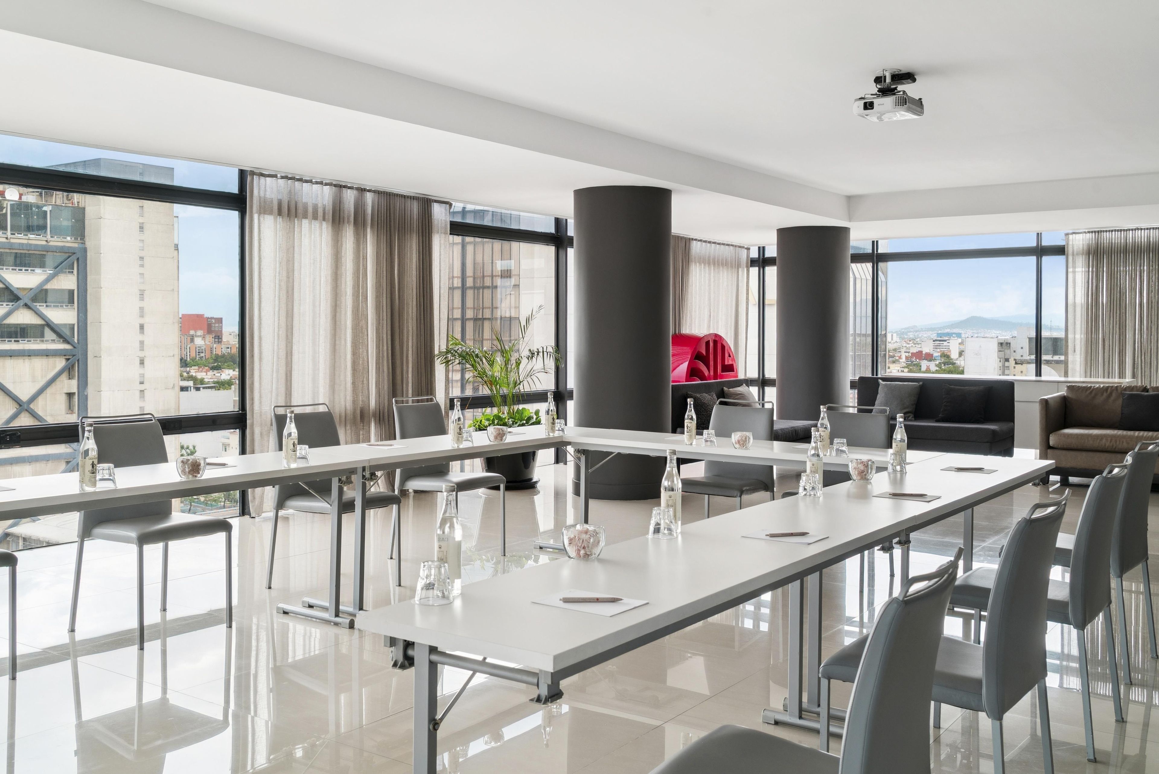 Une salle de conférence moderne, dotée d’une longue table, de chaises et offrant une vue sur la ville.
