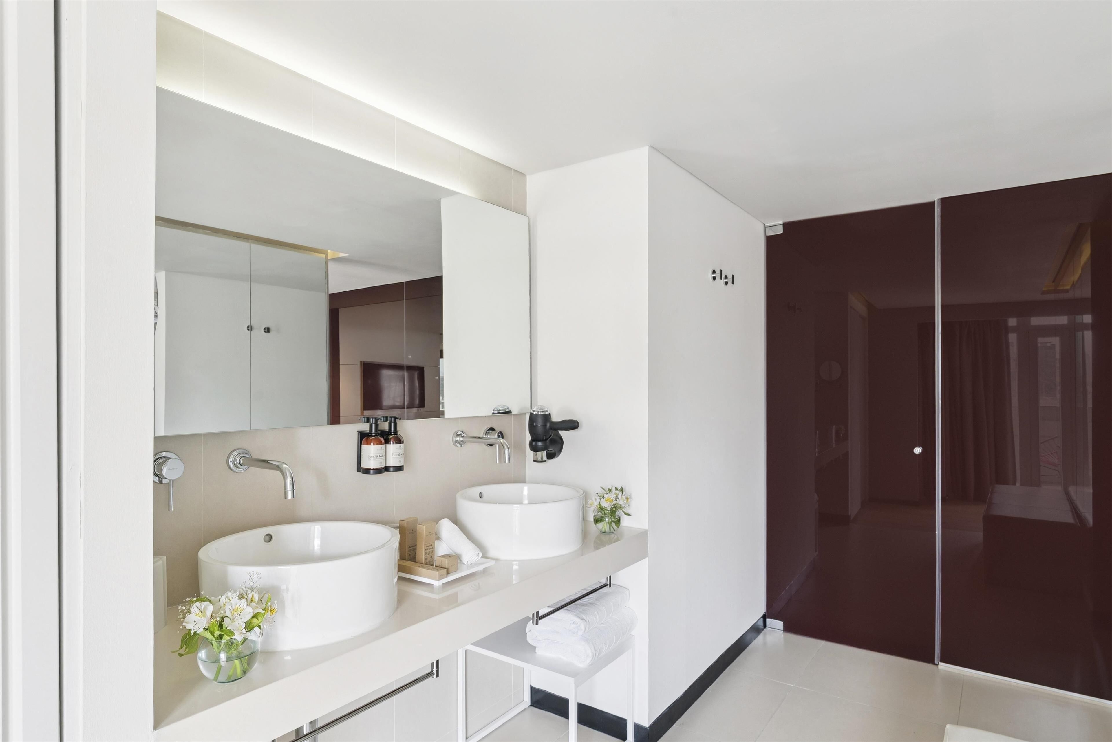 Un baño moderno con dos lavamanos, un espejo grande y una cabina de ducha de vidrio.