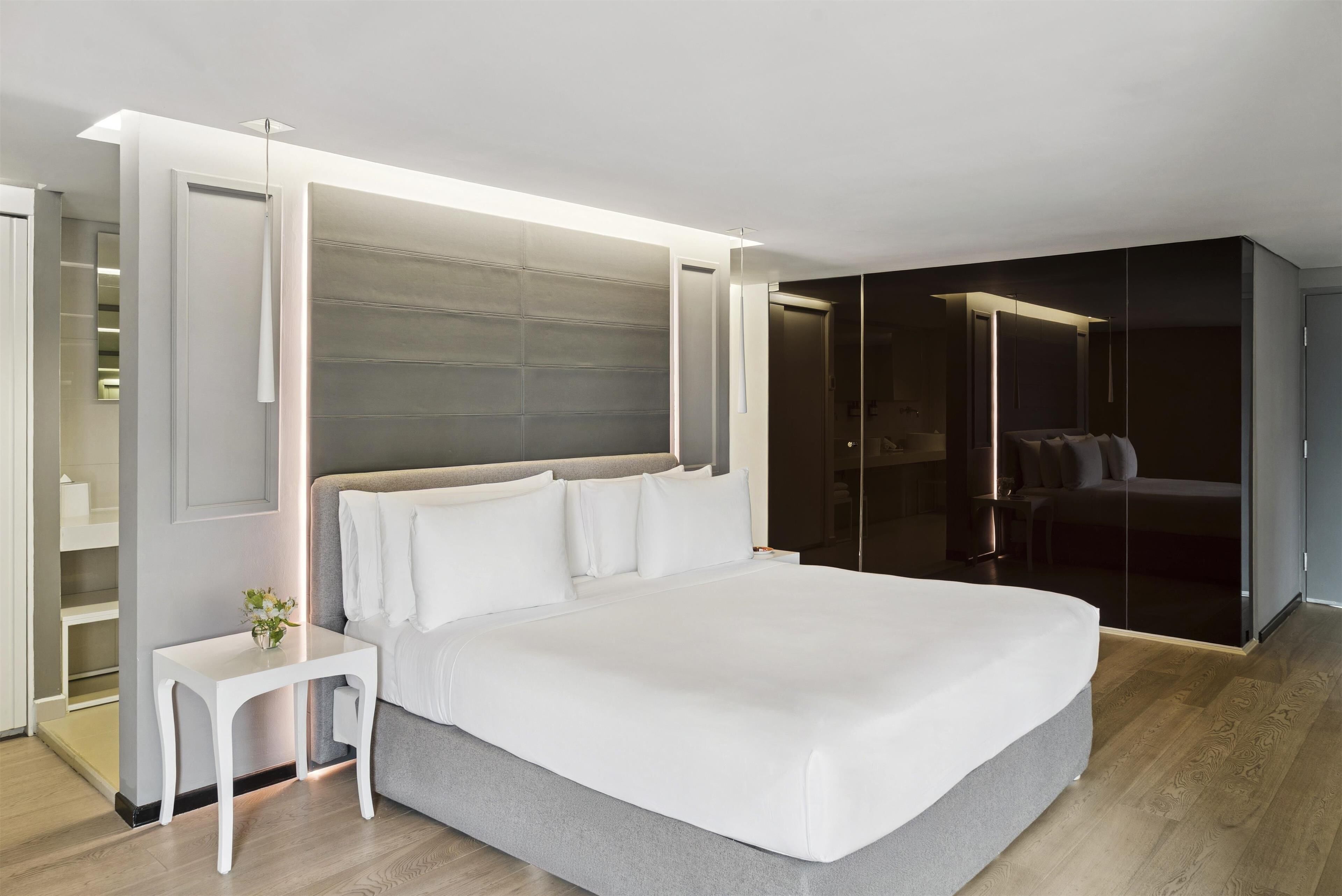 Une chambre moderne avec un grand lit, des tables de chevet, une armoire et un miroir.
