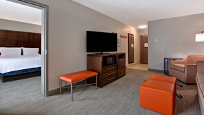 Une chambre d’hôtel comprenant un lit, une télévision, un bureau et un coin salon.