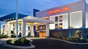 Un hôtel Hampton Inn au design moderne, avec une enseigne « Hampton Inn » bien visible, une entrée accueillante et une façade bien éclairée.