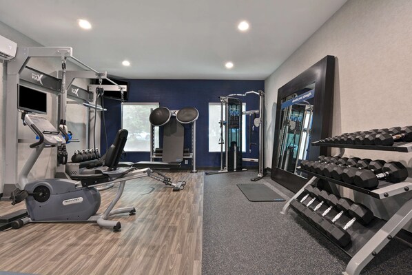 A gym with cardio equipment, weight machines, and dumbbells.