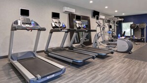 Une salle de sport moderne équipée de tapis de course, d’un vélo d’appartement et d’un rameur.