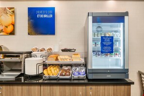 A breakfast bar with a refrigerator stocked with dairy products and a sign offering complimentary yogurt. - Comfort Inn Ancienne-Lorette - Quebec Airport (L'Ancienne-Lorette)