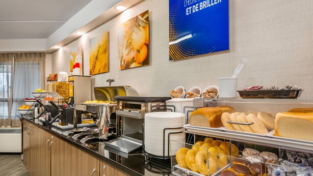 Un espace buffet proposant une variété d’aliments, notamment du pain, des viennoiseries et des fruits.
