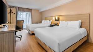 Une chambre d’hôtel avec deux lits, un bureau, une chaise et un téléviseur.