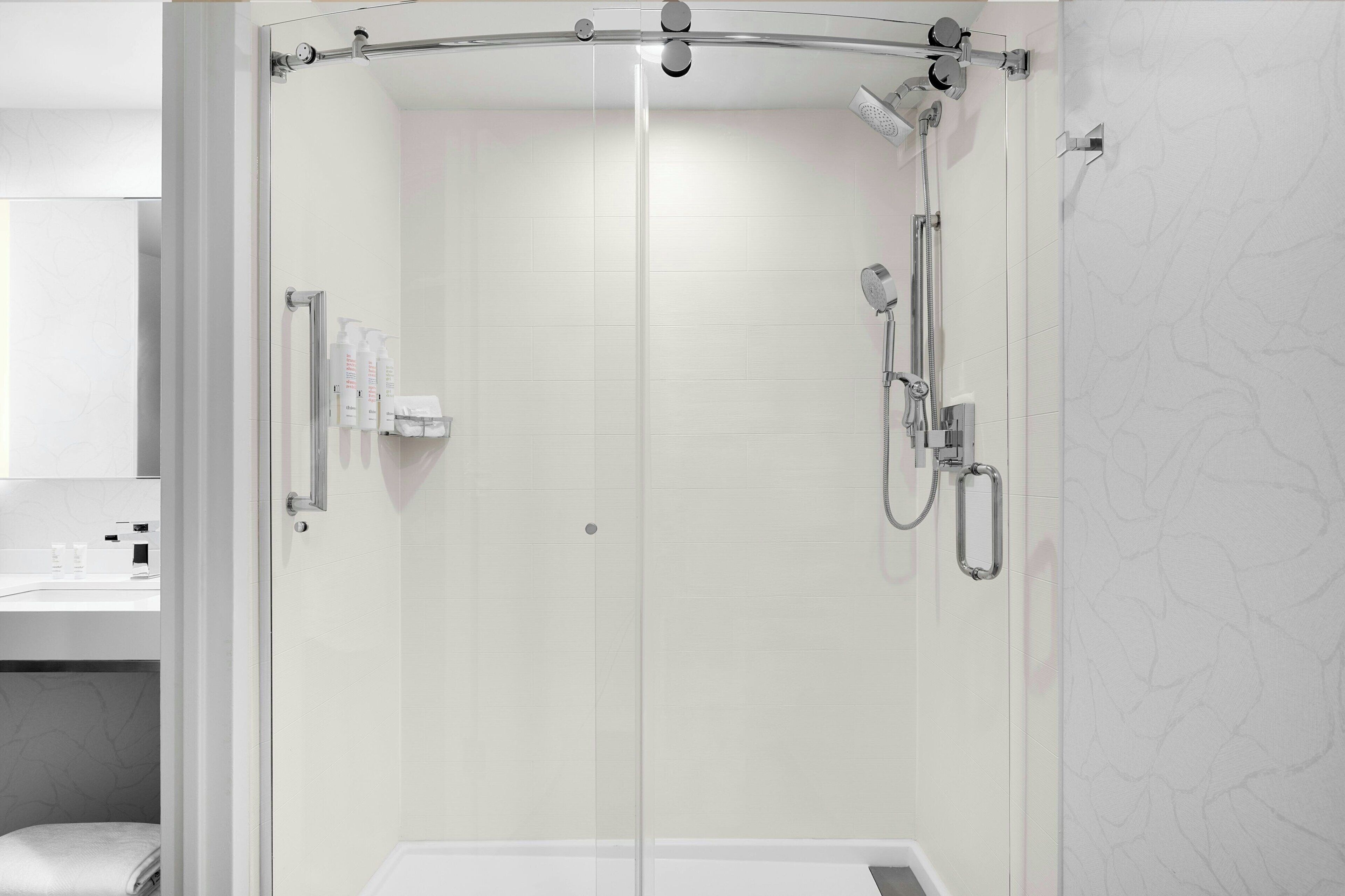 A modern bathroom with a glass-enclosed shower, a toilet, and a sink with toiletries.