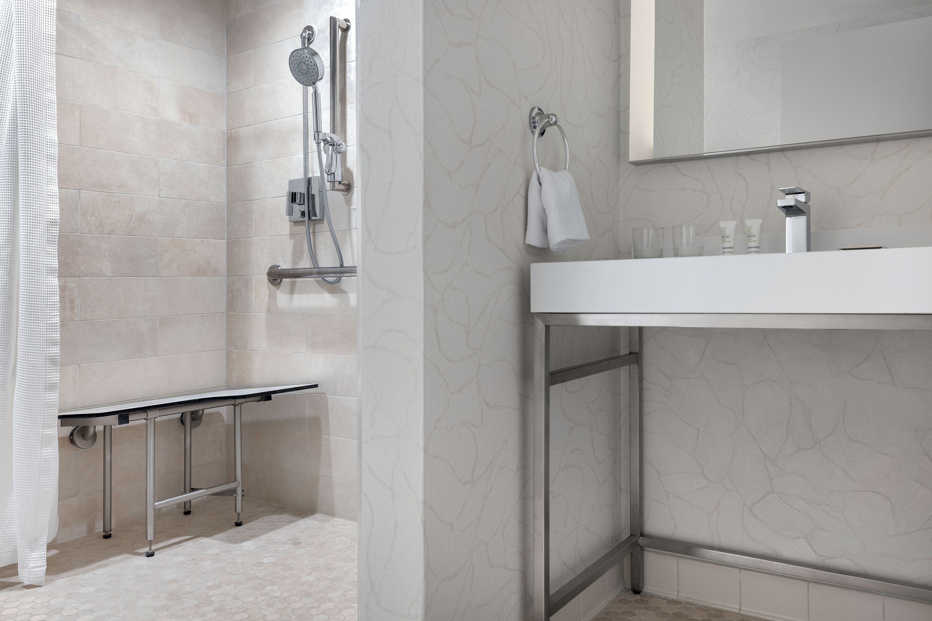 A modern bathroom with a shower, a sink, and a mirror.