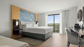 Una habitación de hotel moderna con una cama grande, un escritorio y vistas a la ciudad.