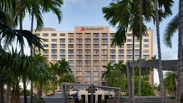 A Marriott hotel with a modern facade, surrounded by palm trees and a covered outdoor seating area.
