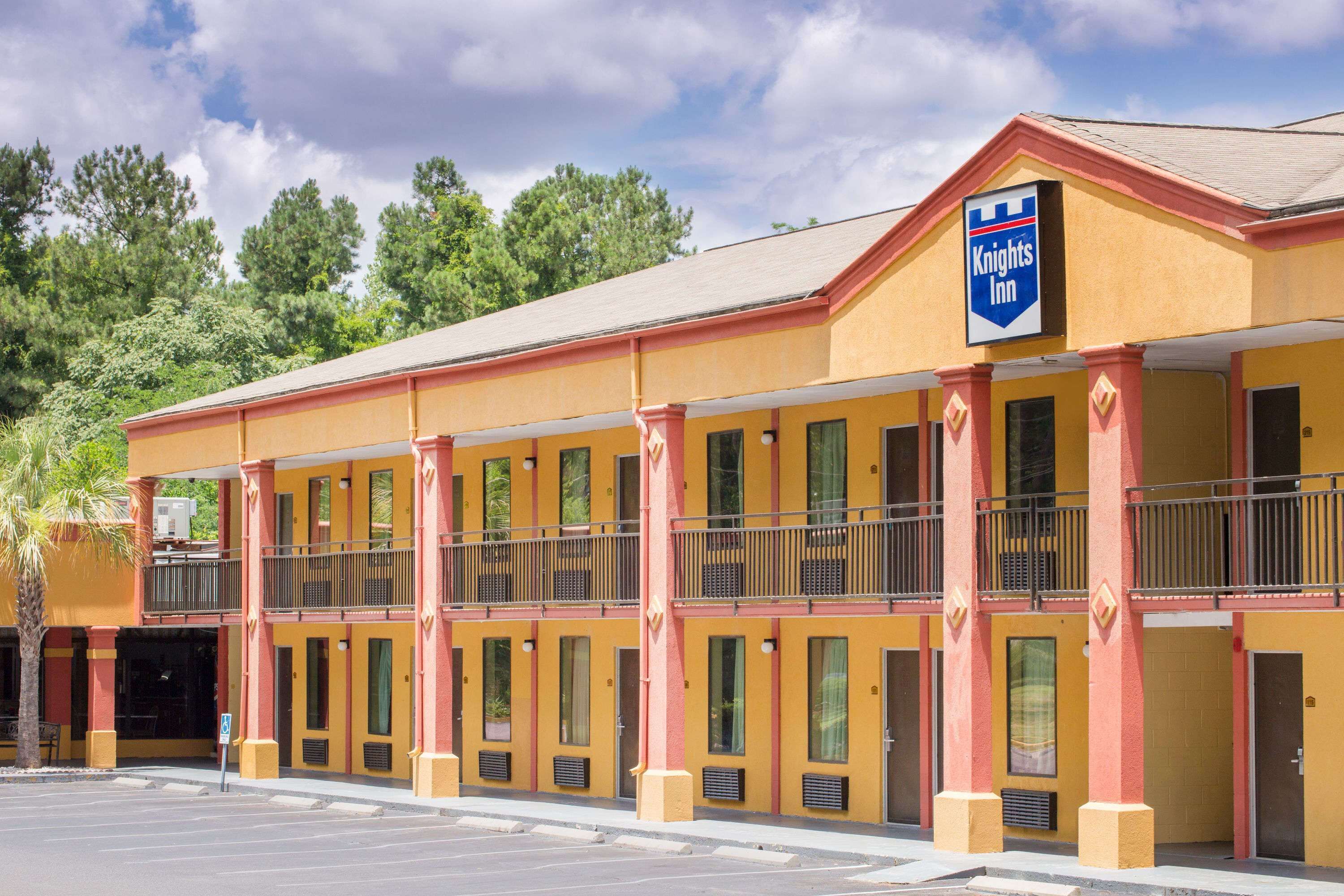 A Knights Inn with a yellow facade, multiple balconies, and a parking lot in front.