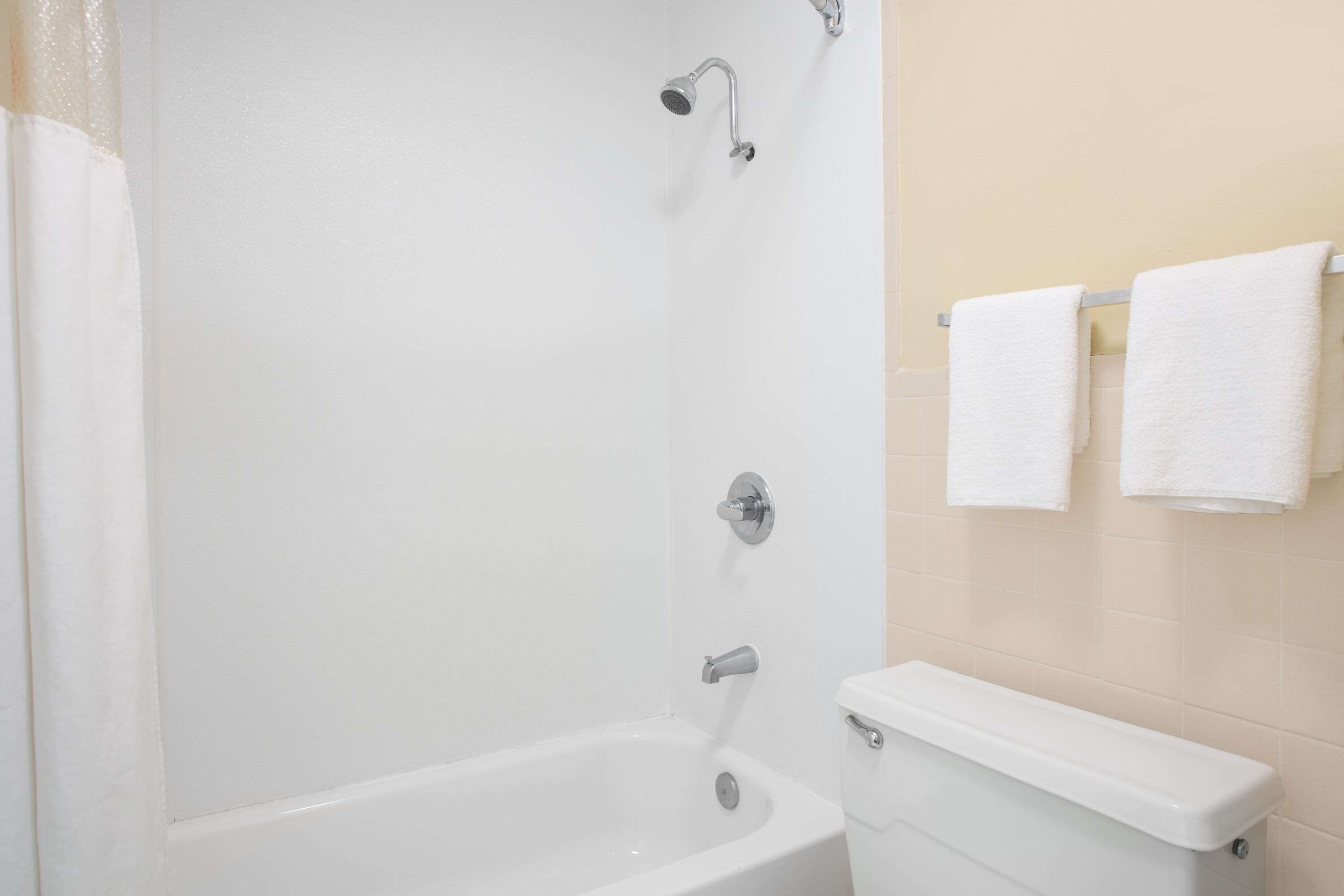 A bathroom with a bathtub, a toilet, and a towel rack with two towels.