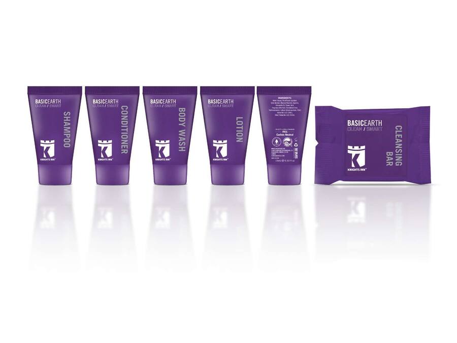 Una hilera de productos de cuidado de la piel morados, incluyendo champú, acondicionador, gel de ducha, loción y un jabón limpiador.