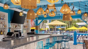 Eine Bar mit einer Theke, blauen Stühlen und hängenden Korblampen.