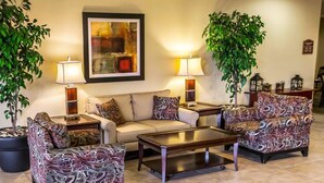 Un salon comprenant un canapé, des fauteuils, une table basse, deux lampes et deux plantes en pot.