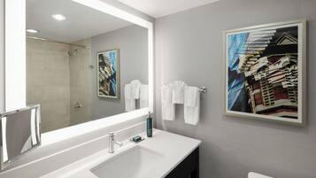 A bathroom with a large mirror, a sink, a toilet, and two framed pictures on the wall.