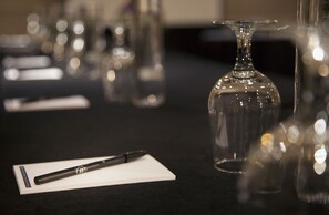 Una mesa con un bolígrafo, una libreta y una botella de vidrio transparente.