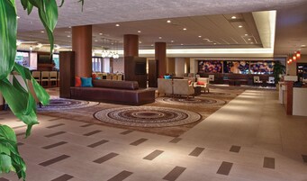 A spacious lobby with a central seating area, a reception desk, and a large decorative wall.
