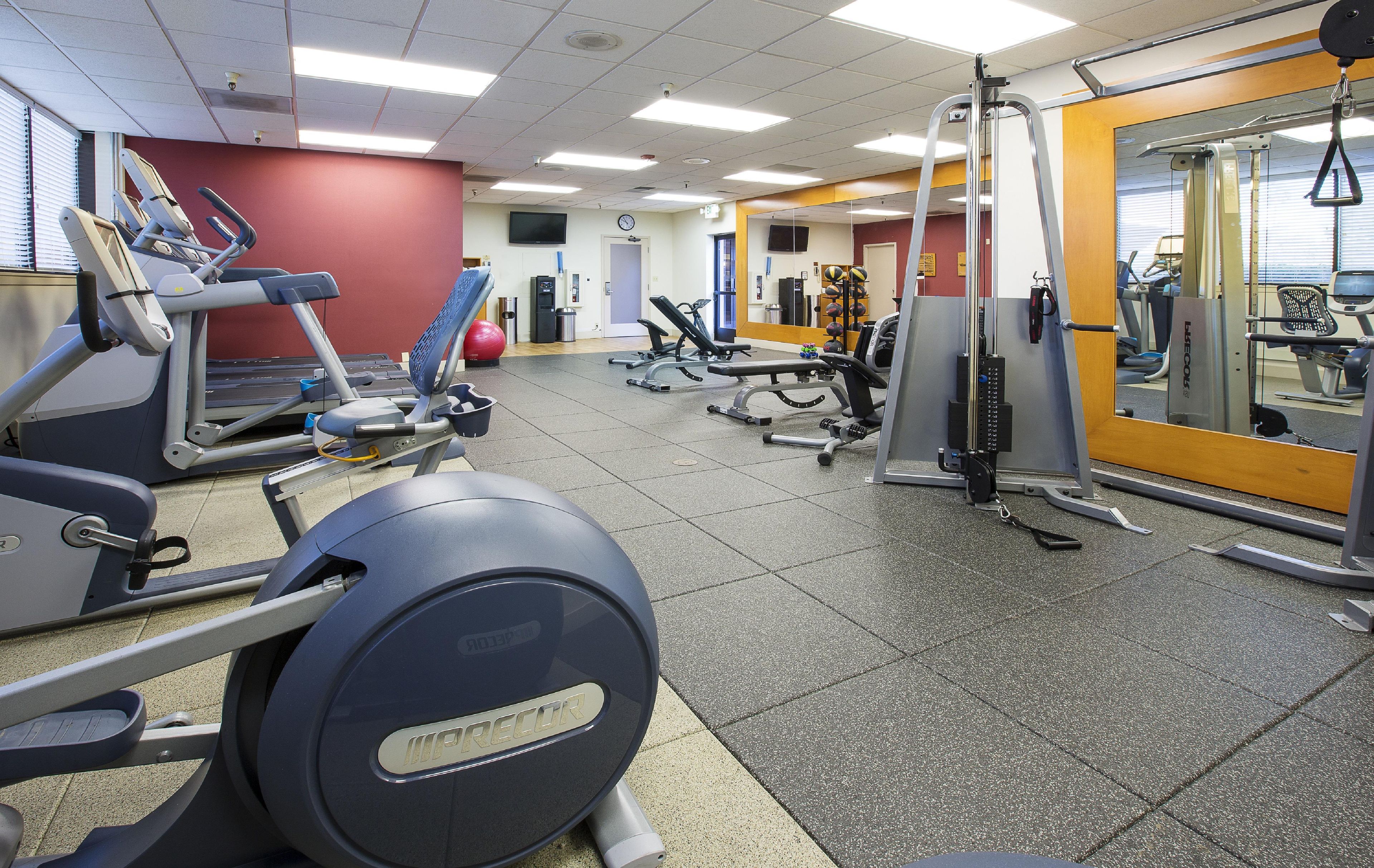 A gym with various exercise equipment, including treadmills, weight machines, and a stationary bike.