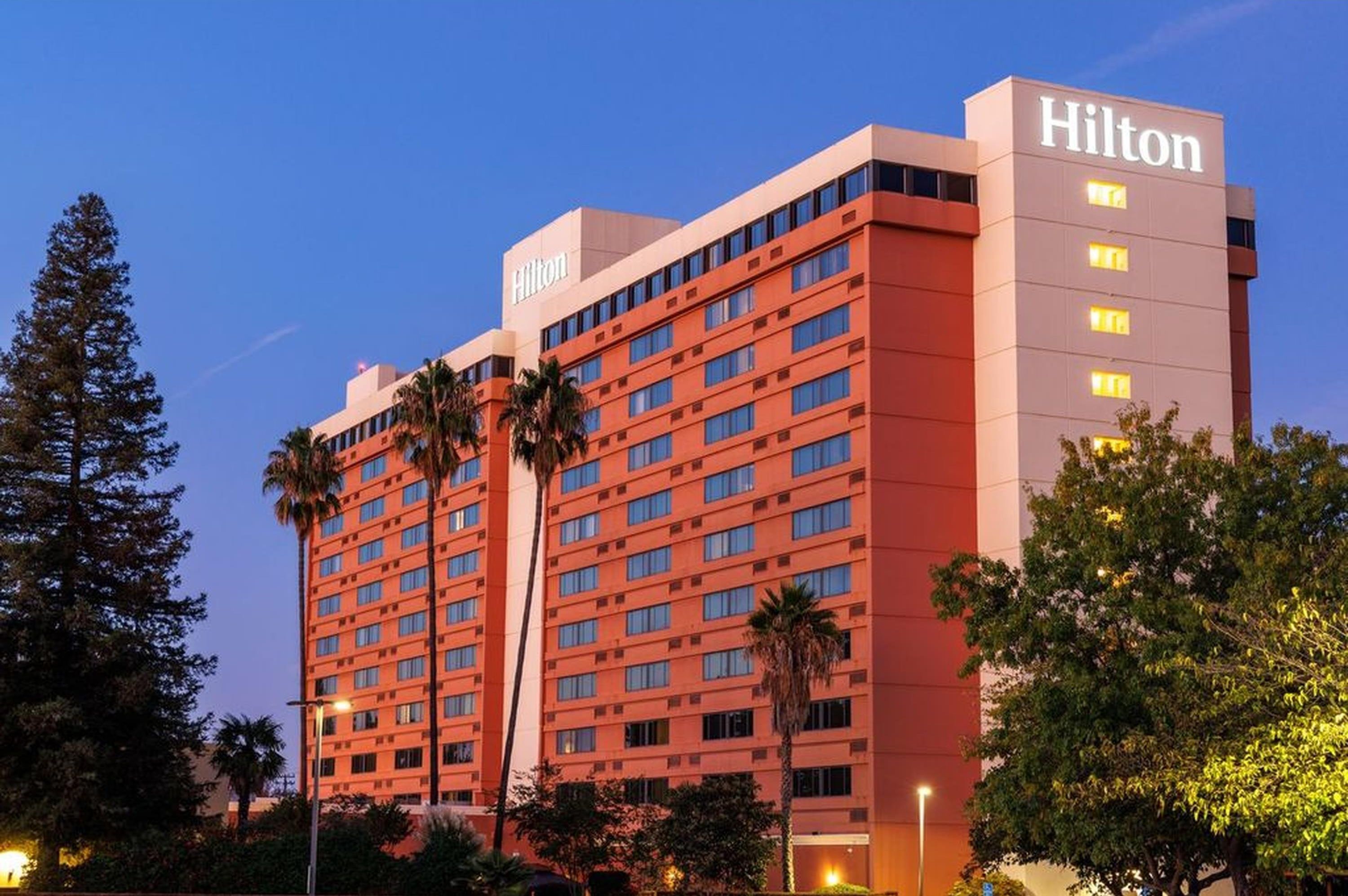 A multi-story Hilton hotel building with a prominent 'Hilton' sign on the top right.