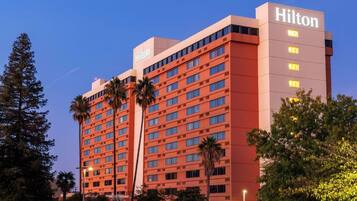 A multi-story Hilton hotel building with a prominent 'Hilton' sign on the top right.