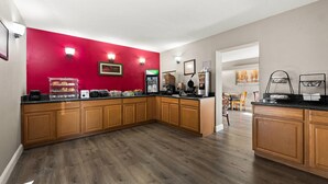 Una cocina con armarios de madera, una pared de acento roja y una barra desayunadora.