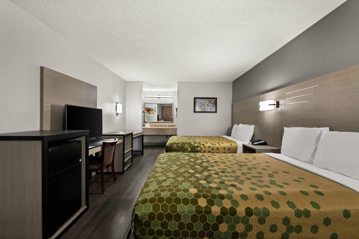 Une chambre d’hôtel avec deux lits, un bureau, une télévision et une petite kitchenette.