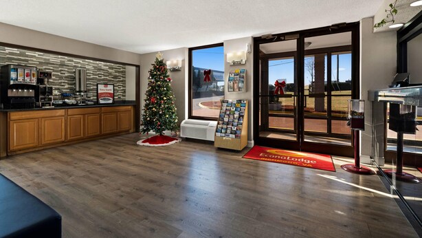 Un moderno vestíbulo de hotel con un mostrador de recepción de madera, un árbol de Navidad, una máquina de café y vistas al exterior.