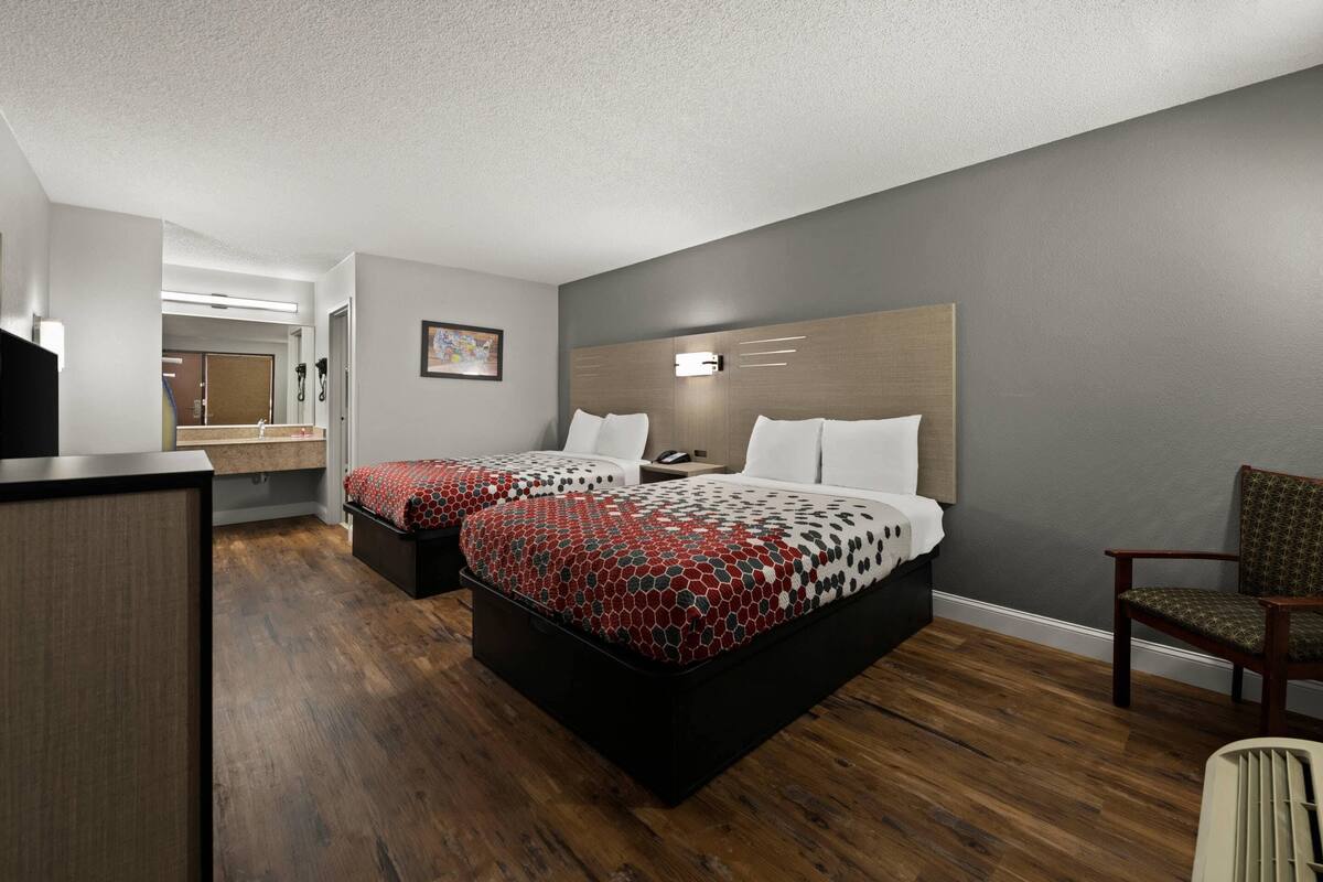 Une chambre d’hôtel avec deux lits, un bureau et une chaise.