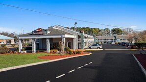Un hotel con un área exterior techada, estacionamiento y un edificio con un letrero que dice "Econo Lodge".