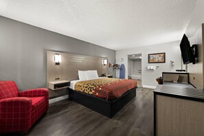 A modern hotel room with a large bed, a red armchair, a desk with a flat-screen TV, and a map on the wall. - Econo Lodge (Richmond)
