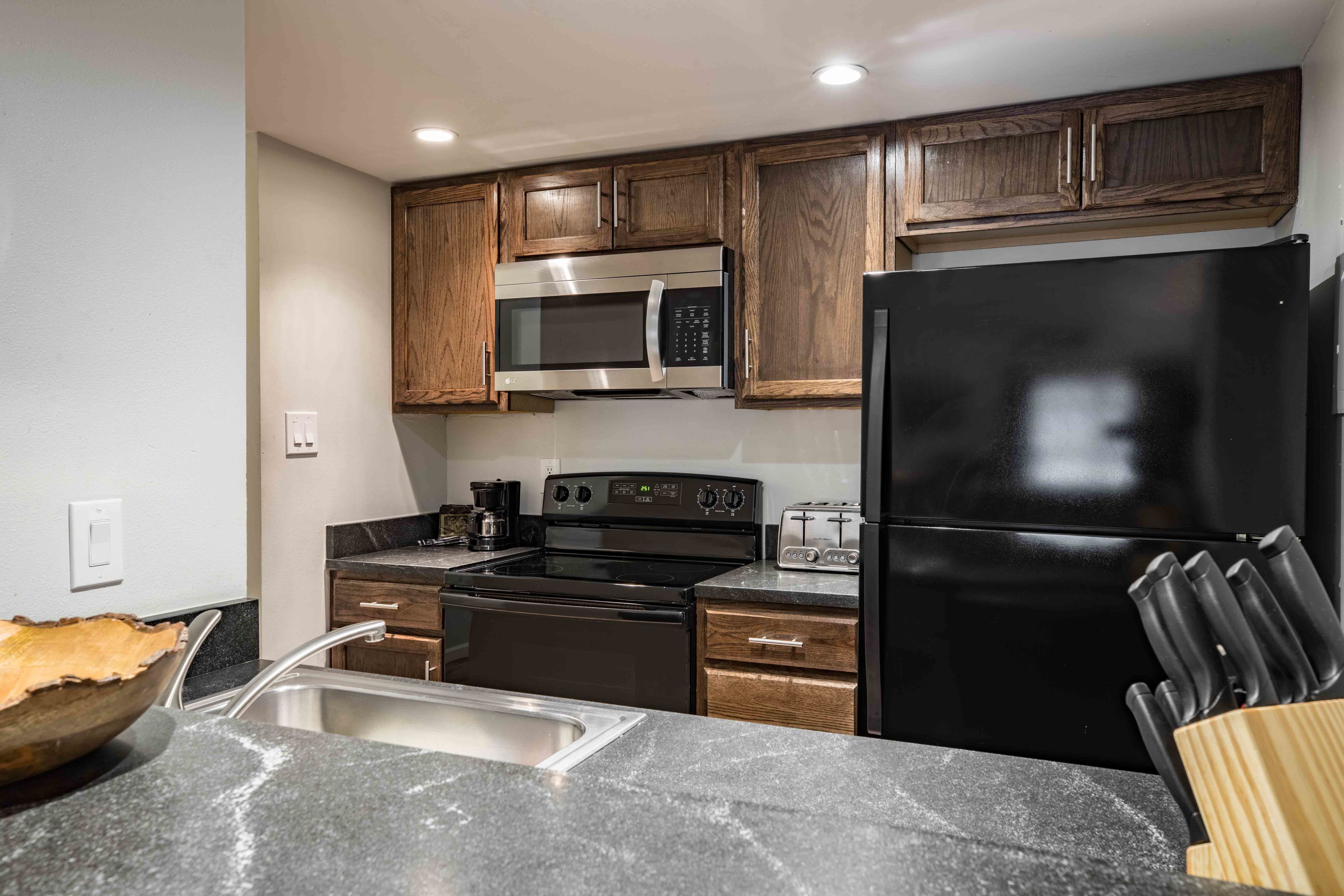 A modern kitchen with wooden cabinets, stainless steel appliances, and a granite countertop.